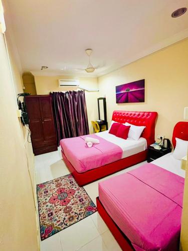 Kampong Bukit BungaBUKIT BUNGA Inn的配有粉红色床单的客房内的两张床