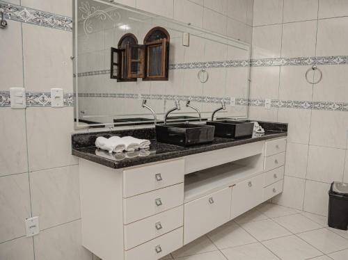 Un baño blanco con lavabo y espejo. en Ev Home, en Cruzeiro do Sul