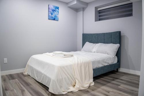 a bedroom with a bed with a white blanket on it at Beautiful Brand New 1BR Suite with Private Entrance and free on-site parking in Winnipeg
