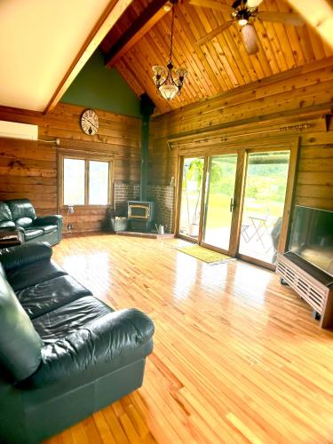 a living room with a leather couch and a television at 実と來-mitoki in Takayama