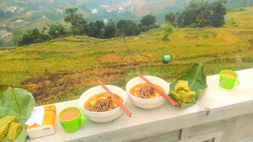 three bowls of food sitting on a ledge with chopsticks at Homestay Quyền Linh-Tour Tây Côn Lĩnh in Kon Rung (1)