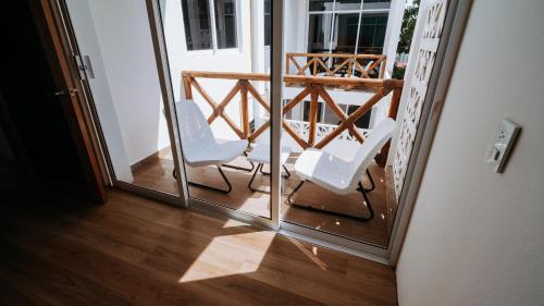 Brisas de ZicatelaAguamiel La Punta的阳台上摆着两把白色椅子，地板是木地板。