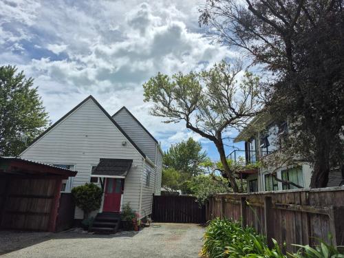 a white house with a fence next to a house at Seaside Tahuna in Nelson