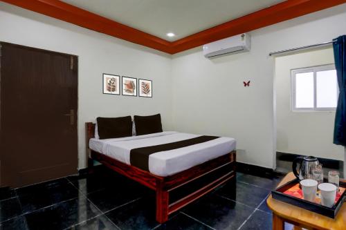 VadarevuHotel O Chirala Beach View Formerly Sea Shell Resort的一间卧室，里面有一张床、一张桌子和一扇窗户