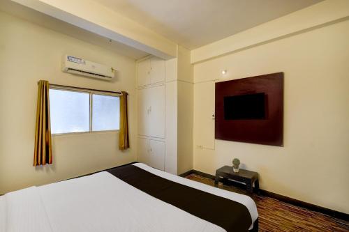 a bedroom with a white bed and a window at Super Hotel O Laxmi Narsimha Temple Banjara Hills in Hyderabad
