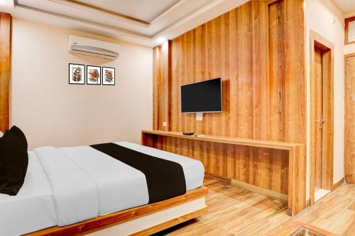 デヘラードゥーンにあるTownhouse Oak Dehradun Court Formerly GK Residencyのベッドと薄型テレビのある寝室