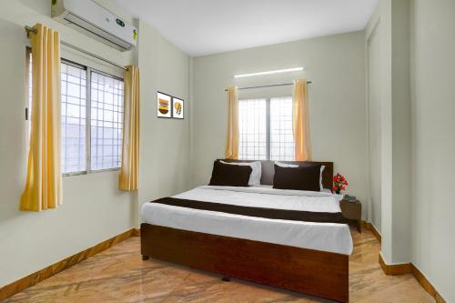 a bedroom with a large bed and two windows at Super Hotel O Symbiosis University Nagpur Formerly Royal Villa Inn in Sakardarā