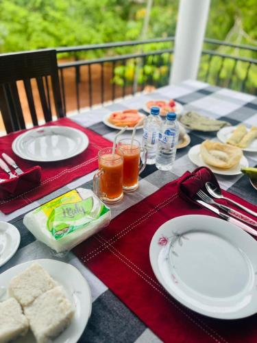Una mesa con platos de comida y bebidas sobre ella. en Sigiriya Arecanut Garden, en Sigiriya