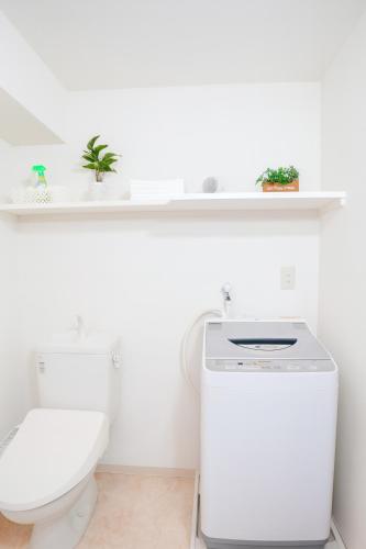 a white bathroom with a toilet and a shelf at LIO HOTEL Tokyo Nippori in Tokyo