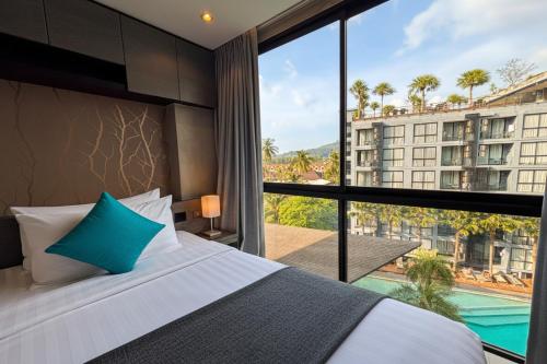 a bedroom with a bed and a large window at Wellness Hub 2BR Pool View - CTG B503-4 in Kamala Beach