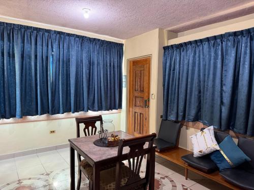 a living room with blue curtains and a table at Departamento Nuevo Céntrico con vista hacia la catedral in Saltillo