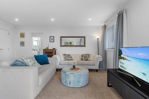 a living room with a couch and a flat screen tv at Endless Summer Retreat - Mt Maunganui in Mount Maunganui