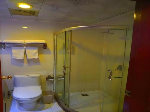 a bathroom with a toilet and a glass shower at GreenTree Inn Xi'an Bell and Drum Tower Food Street Ancient City Wall Ximen Express Hotel in Xi'an