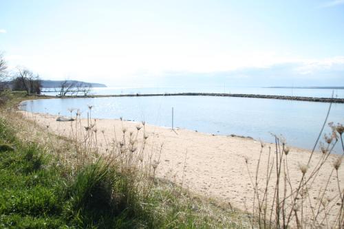 a sandy beach with a pier in the water at First Camp Gränna - Vättern in Gränna