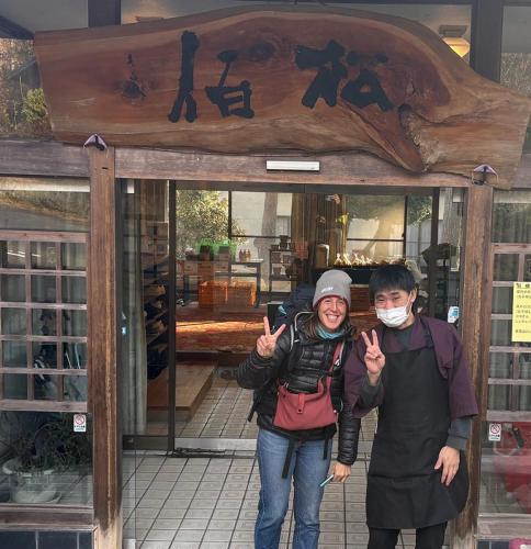 a man and a woman standing in front of a store at 檜湯の宿　松伯 in Aoki-gemi