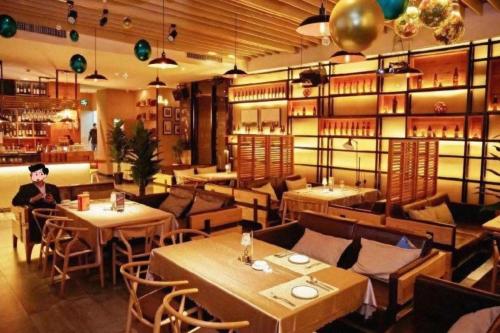 um restaurante com mesas e cadeiras e um homem sentado no meio em City Comfort Inn Shantou Huashan Road the MixC em Ma Yu