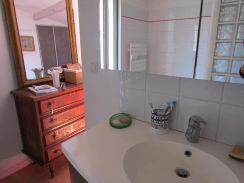 a bathroom with a sink and a mirror and a dresser at Les Garrigues Bleues in Tornac