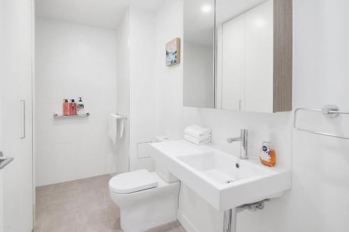 a white bathroom with a sink and a toilet at Riverside Modern Living 2B2B Apt with Parking in Brisbane