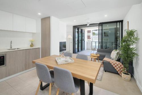 a kitchen and dining room with a wooden table and chairs at Riverside Modern Living 2B2B Apt with Parking in Brisbane