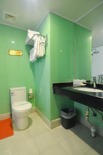 a bathroom with a toilet and a sink and a mirror at Qinhuangdao Yang Cheng Hotel in Qinhuangdao