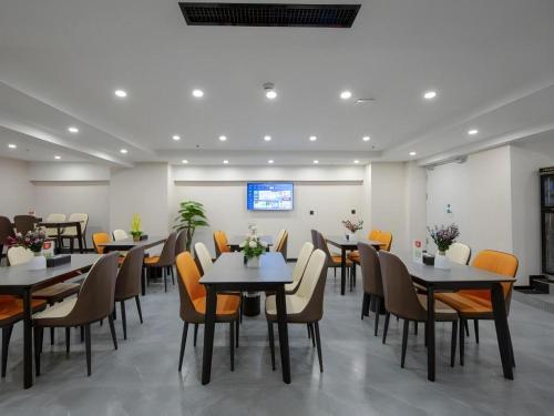 a dining room with tables and chairs and a screen at Green Tree Inn Express Heze University Town in Zhaolou