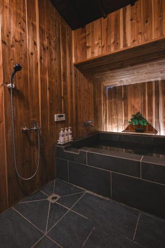 a bathroom with a shower with wood paneled walls at Naikumae Bettei Hoshiakari in Ise