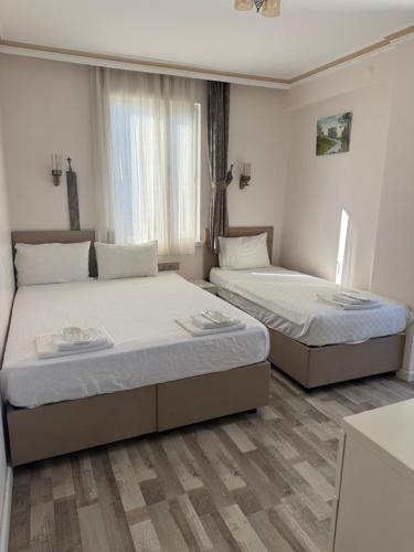 two beds in a room with white walls and wooden floors at Send Apart Otel in Antalya