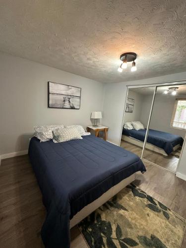 a bedroom with a blue bed and a mirror at Private Room Lakeview House- Westmount in Moncton