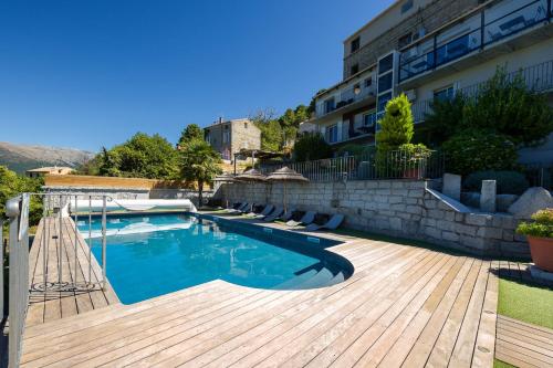 a swimming pool on a wooden deck next to a building at Hotel Le Tourisme in Zonza