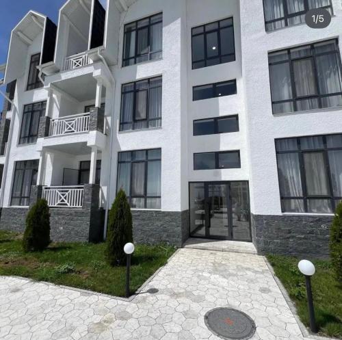 a large white building with black windows at Апартаменты в Чайка Резорт, Иссык-Куль in Chon-Sary-Oy