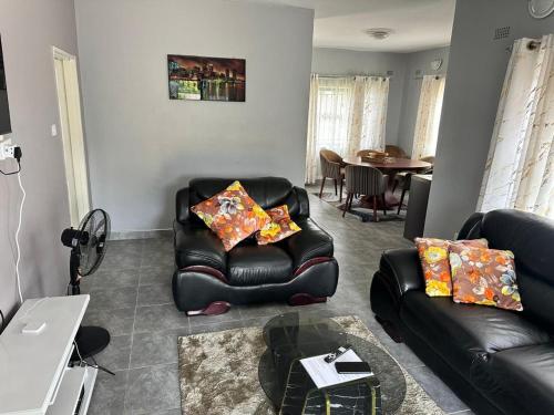 una sala de estar con una silla de cuero negro y una mesa en Hatfield staylax Manor 1, en Harare