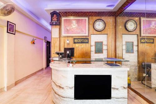 a lobby with a counter with clocks on the wall at Hotel O Durgapuri Metro Station Lucknow Formerly Pal Awadh in Bādshāhnagar
