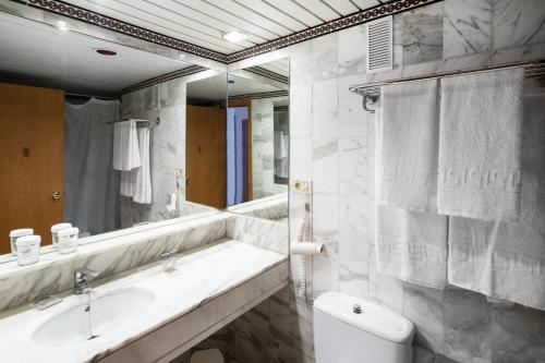 a bathroom with a sink and a toilet and a mirror at Catalonia Las Vegas in Puerto de la Cruz