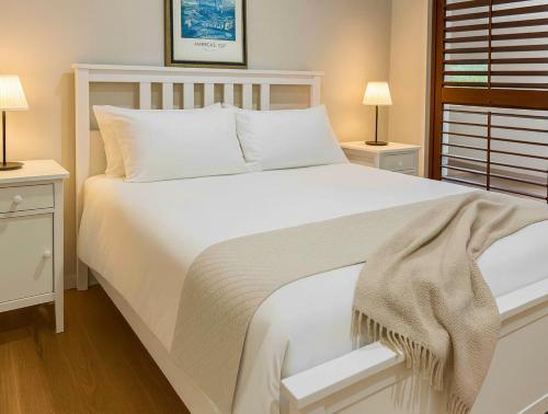 塔勒布吉拉Tallebudgera Hinterland Retreat的卧室里有一张白色的大床，床边还有两盏灯