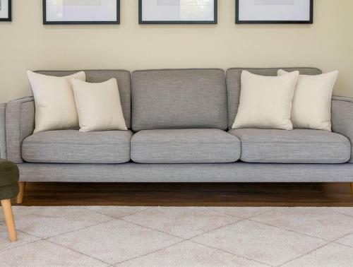 a gray couch with three pillows in a living room at Tallebudgera Hinterland Retreat in Tallebudgera