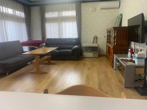 a living room with a couch and a table at Shiro の秘密基地 駐車場無料 in Ōmagari