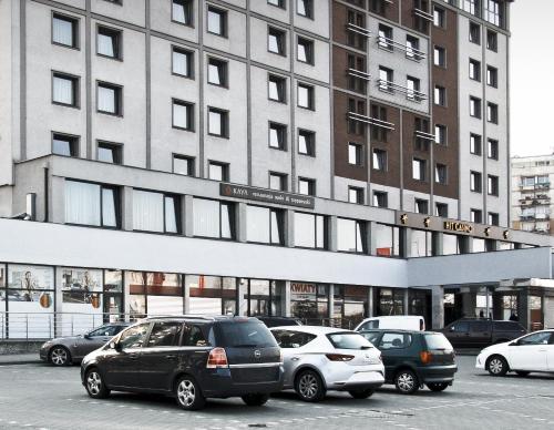a parking lot with cars parked in front of a building at Hotel Tychy in Tychy