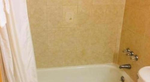 uma casa de banho com uma banheira branca e um chuveiro em Travelodge by Wyndham Bay Shore Long Island em Bay Shore