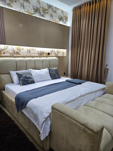 a bedroom with a large bed and a couch at Mohills Apartment Wuye in Abuja