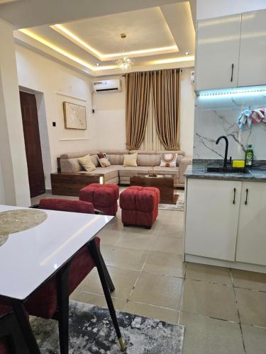 a kitchen and a living room with a couch at Mohills Apartment Wuye in Abuja