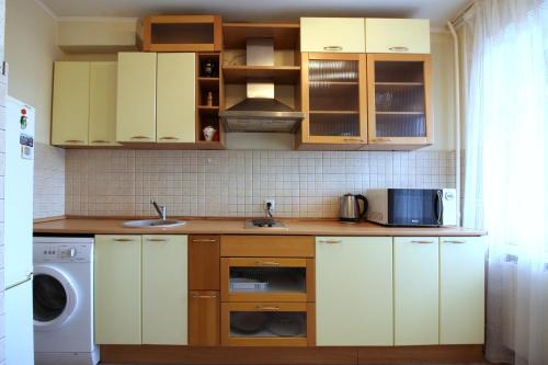 モスクワにあるApartments on Ukrainskiy bul 8の白いキャビネット、シンク、洗濯機付きのキッチンが備わります。