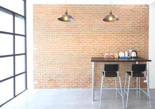una pared de ladrillo con una mesa y dos taburetes en L22 HOSTEL, en Ban Khlong Samrong