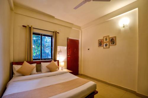 um quarto com uma cama grande com janela em Aqua Wave by YogiTree Hotels em North goa