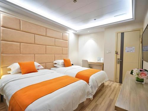 two beds in a hotel room with orange at Shell Shanghai Baoshan District Songbin Road Subway Station Hotel in Hujiazhai