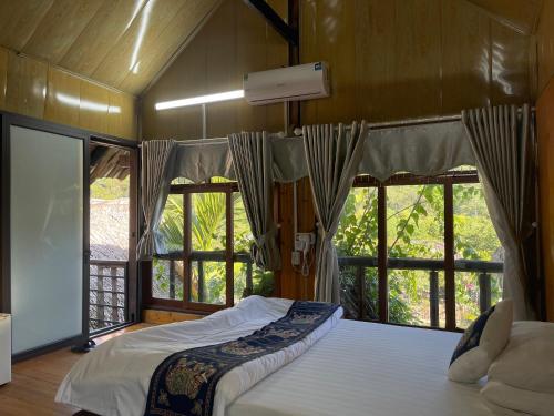 ein Schlafzimmer mit einem Bett in einem Zimmer mit Fenstern in der Unterkunft Ba be farmstay in Ba Be18