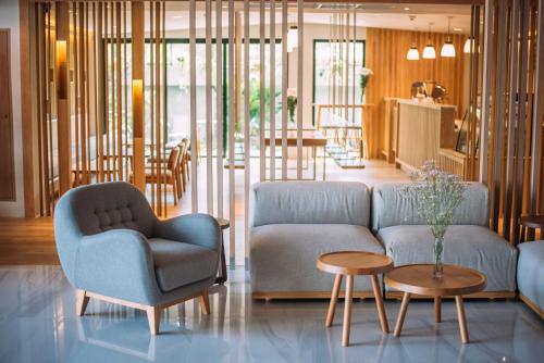 a living room with a couch and chairs and tables at Mii Hotel Srinakarin in Bangna