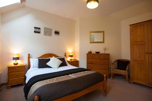 バラターにあるGlenernan Self Catering Cottagesのベッドルーム1室(ベッド1台、ドレッサー、ランプ2つ付)