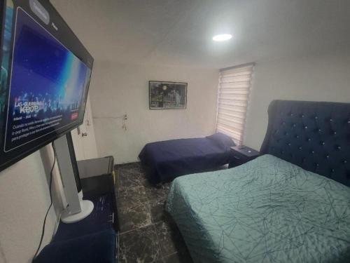 a bedroom with a bed and a flat screen tv at Águilas Room 2 camas in Guadalajara