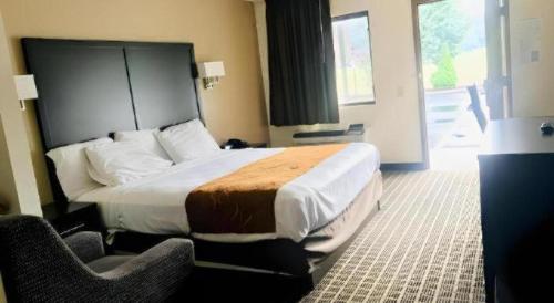 a hotel room with a large bed and two chairs at Baymont by Wyndham Acworth in Acworth