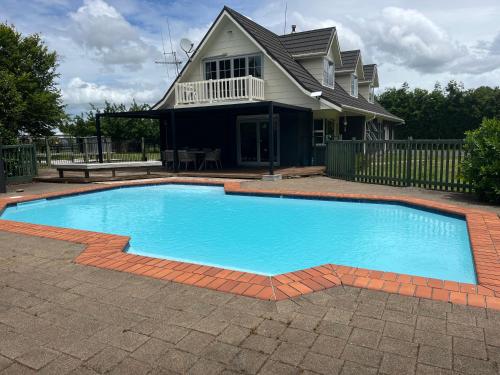 a large blue swimming pool in front of a house at Hamilton Greenhill Lodge - Private Pool & Easy Highway Access in Hamilton